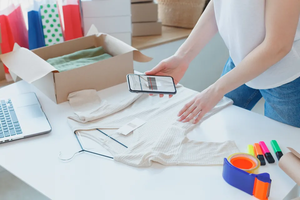 スマートフォンで商品の服を撮影する人