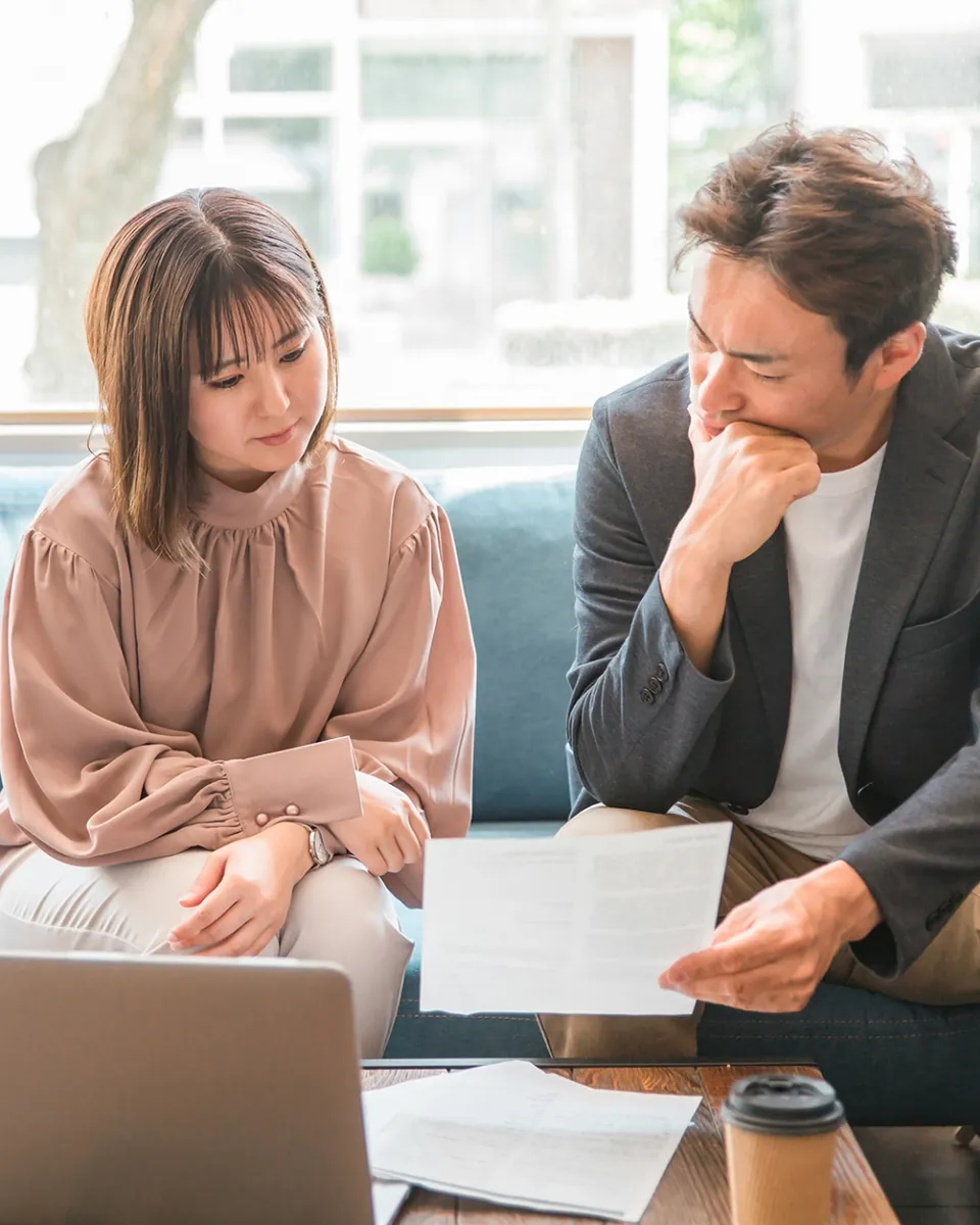 カフェの席で書類を見ながら打ち合わせをする2人